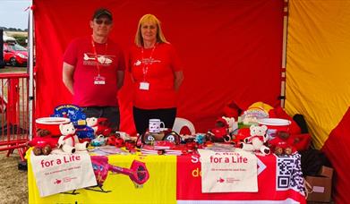 Two people stand behind a pop-up market stall, raising money for a charity
