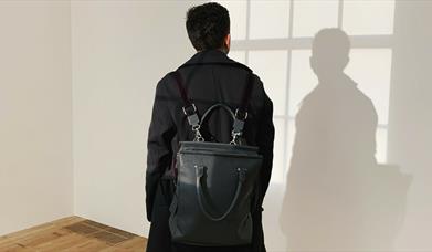 Person with black backpack and dark jacket looking at wall