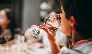 A person drinking from a clear wine glass