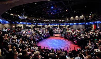 New Vic Theatre, Newcastle under Lyme theatre in the round. Image shows the auditorium filled with people.