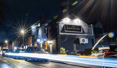 The Fountain Inn, Leek, captured from the street at night, with light trails from the cars passing by