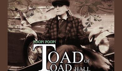 A black and white photo of a man in a suit sitting beside a classic car