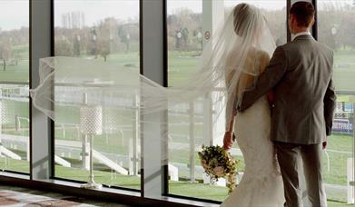 A couple, on their big day, gaze out over the racecourse