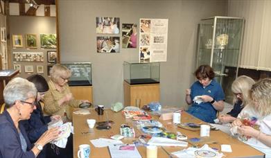 A group of crafters work on their project around a table