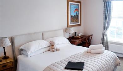 Bedroom with double bed, bedside tables, towels on the bed, and a teddy sitting between the pillows