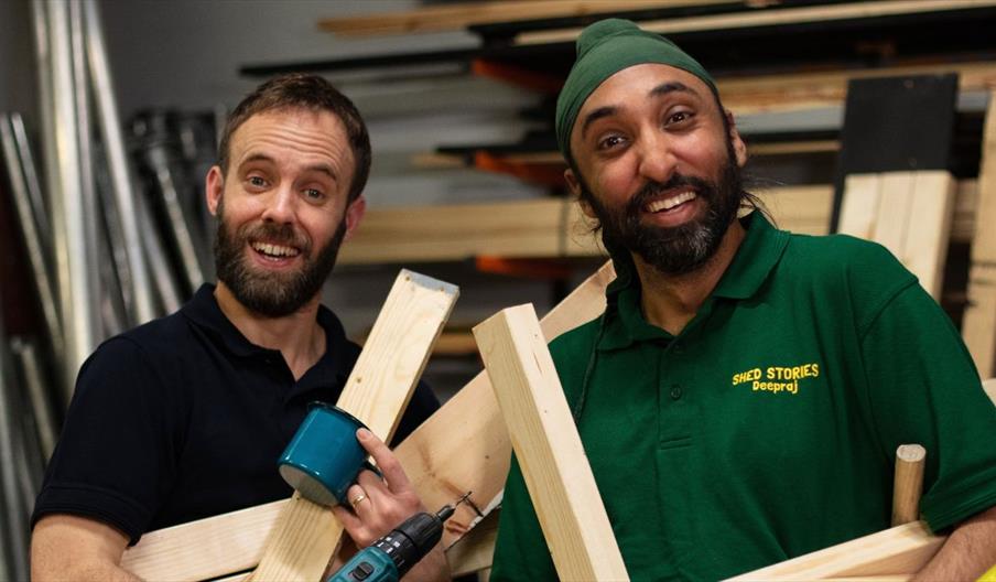 Two men holding wooden items from a shed