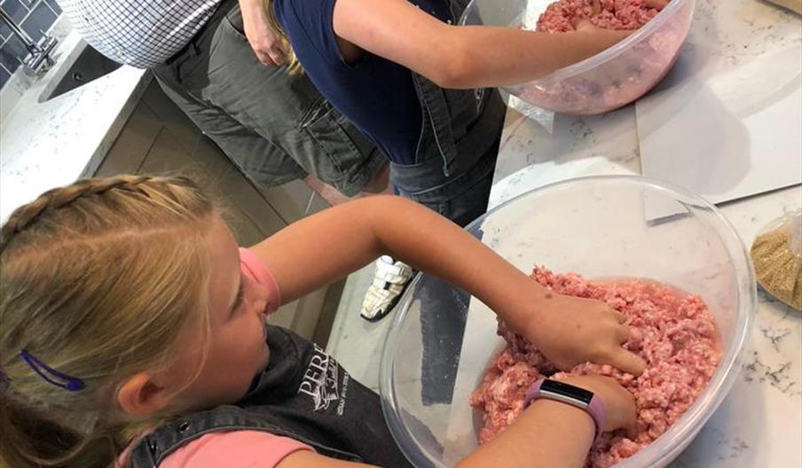 photo showing 2 children being guided through the making of pork pies