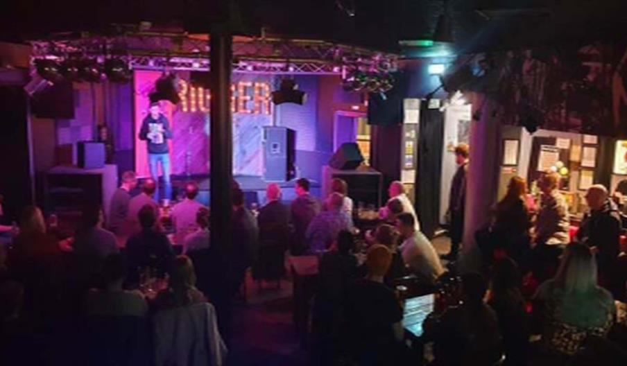 Image shows a crowd of people in a bar enjoying live stand-up comedy
