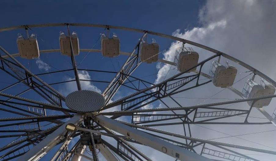 A ferris wheel against a blue sky with white fluffy clouds