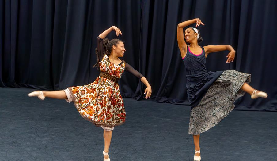 Two black ballet dancers mid-performance on stage