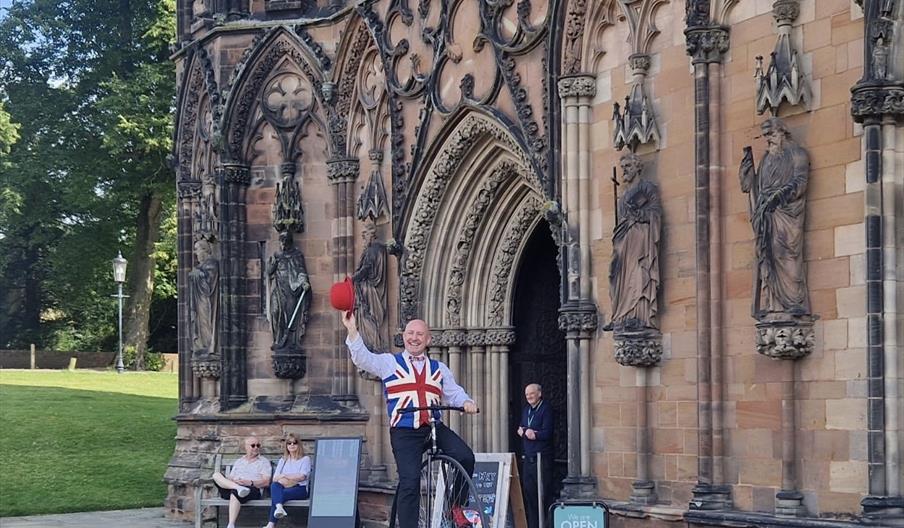 Man on Penny Farthing bicycle in front of Lichfield Cathedral