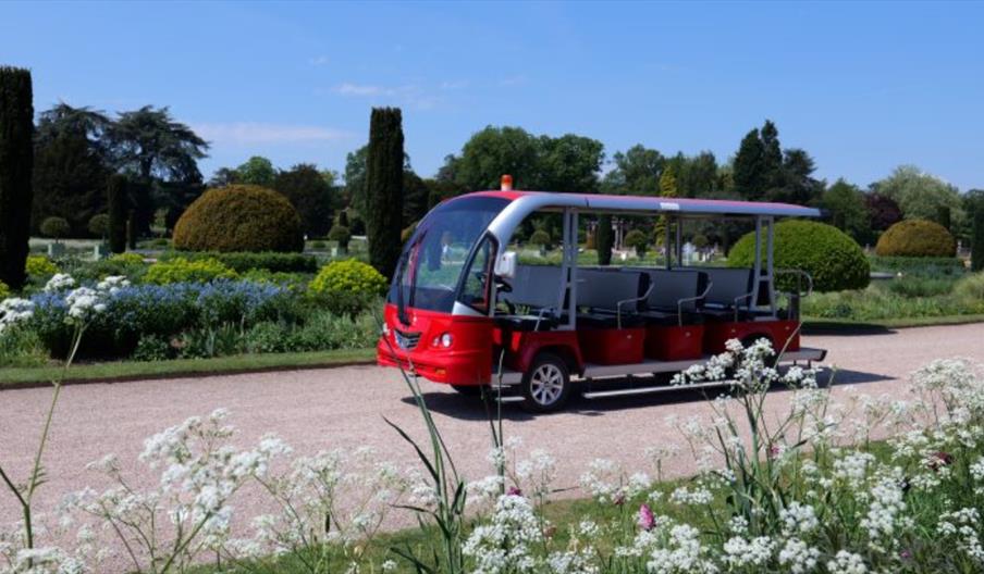 A red bus surrounded by flowers and gardens