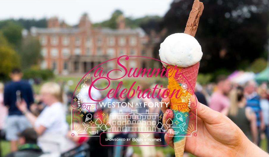 hand holding a ice cream in the foreground, with a park and stately home in the background
