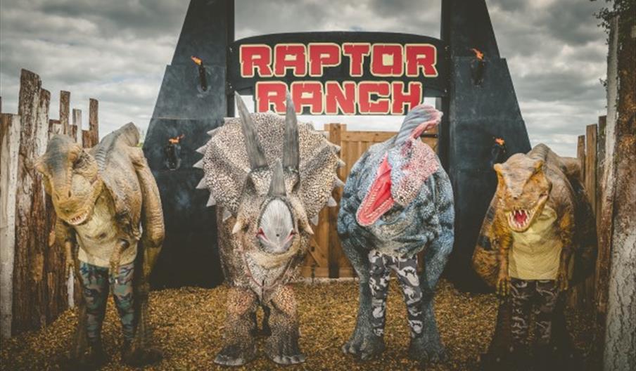 Four dinosaurs stand outside the Raptor Ranch at the National Forest Adventure Farm