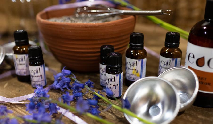 An aromatherapy kit, with bottles, lavender, bowls, and other tools including a whisk, on a table