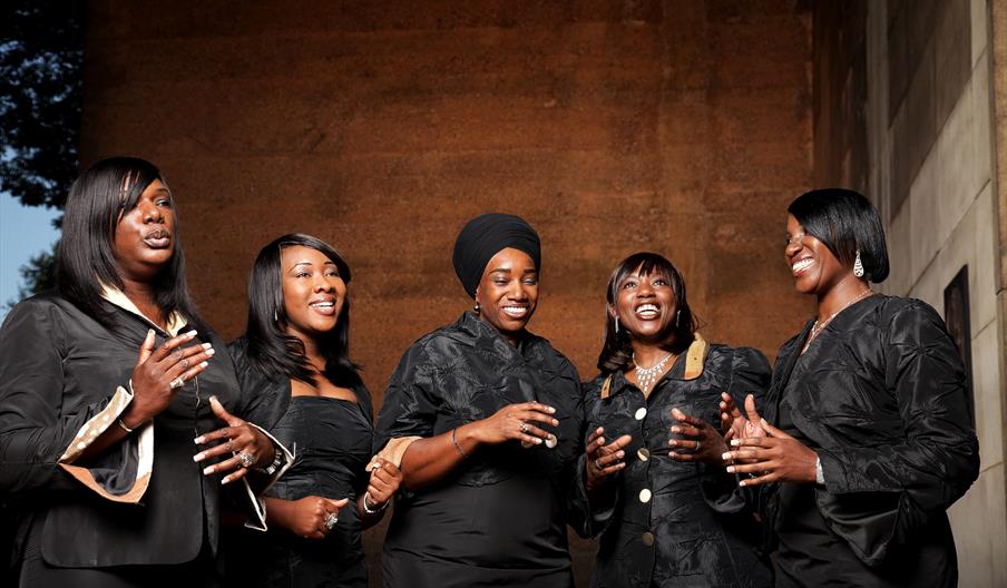 Image shows the five women of Black Voices preparing for a performance