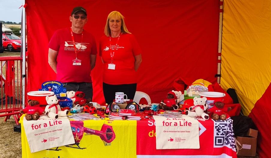Two people stand behind a pop-up market stall, raising money for a charity