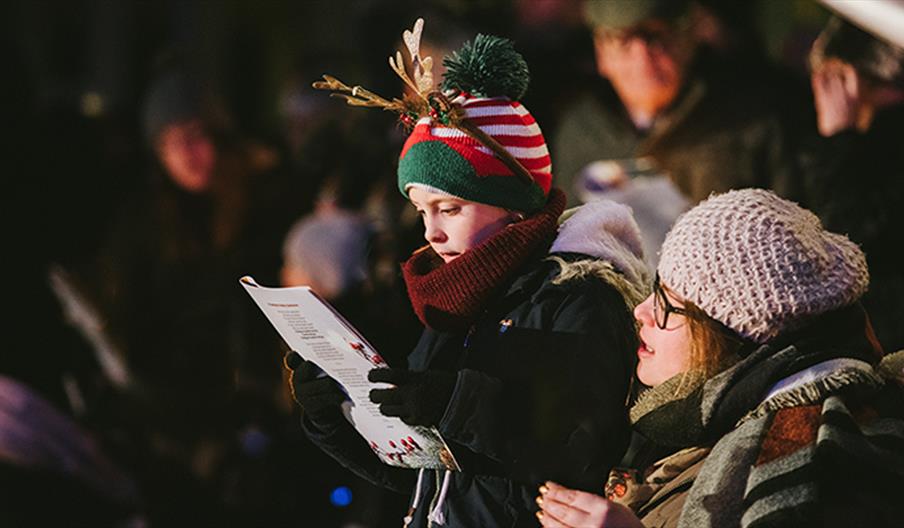 A festive looking family sing Christmas carols at the National Memorial Arboretum, Staffordshire
