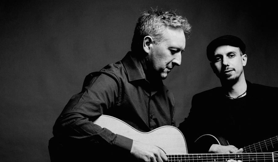 Image shows two musicians with guitars, in black and white