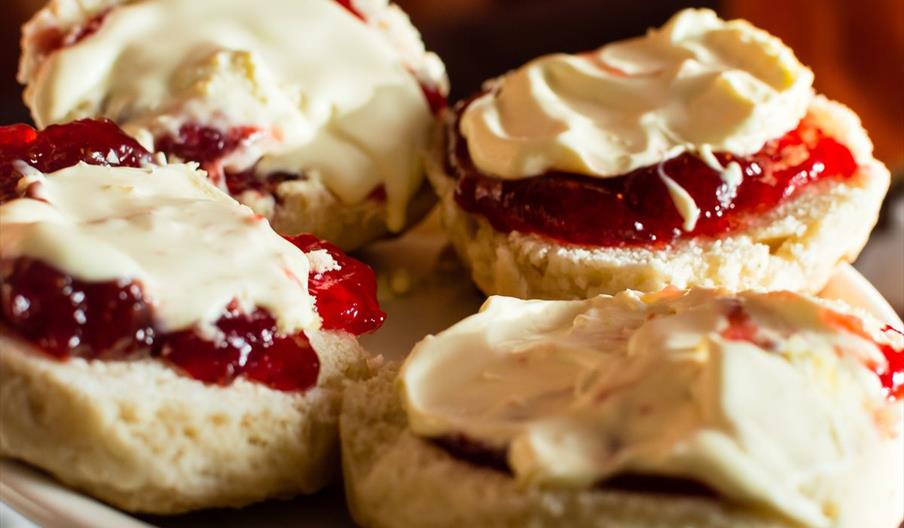 A mouth-watering image of scones with jam and cream