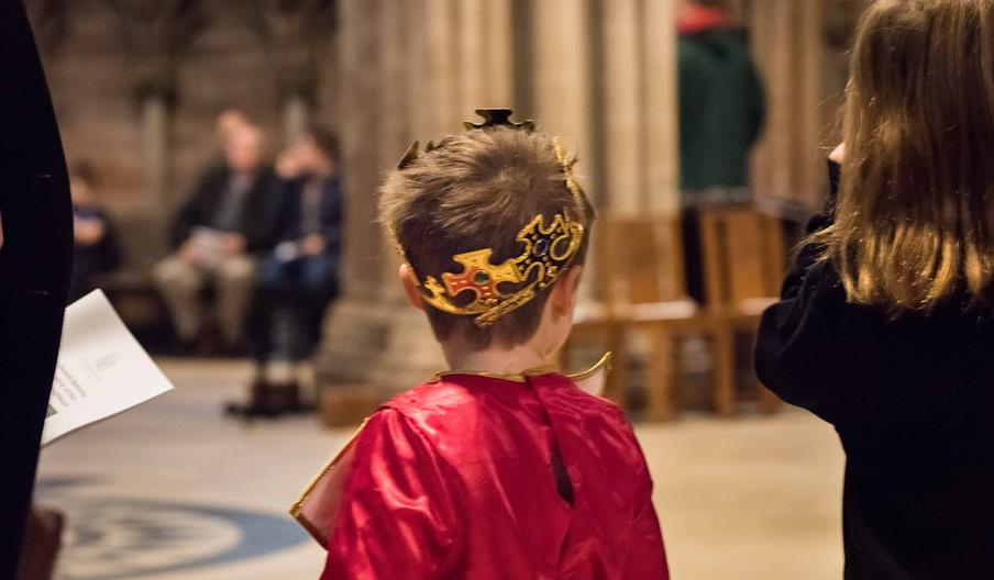 Image shows a youngster, inside Lichfield Cathedral, wearing a crown and costume