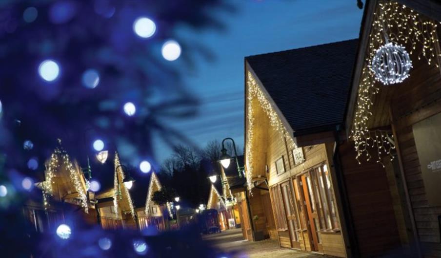Timber lodges with Christmas lights at Trentham Shopping Village, Staffordshire