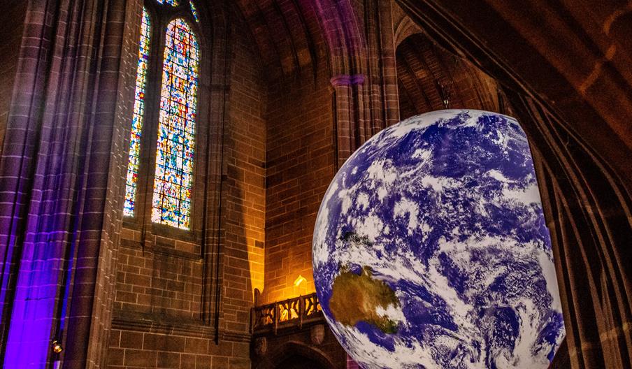 Image shows a huge model of Planet Earth, suspended from the ceiling of a Cathedral