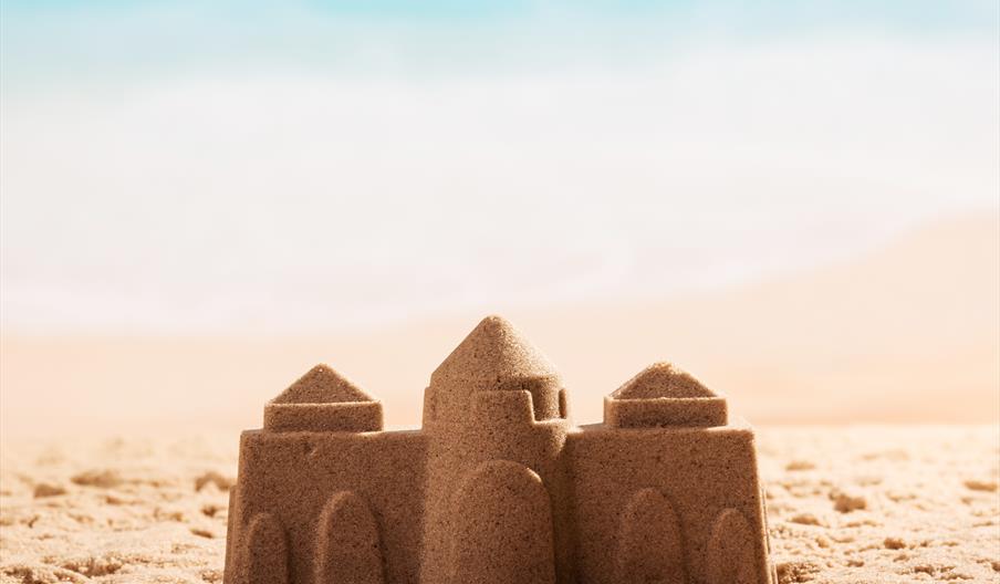 Image shows a sandcastle on a beach