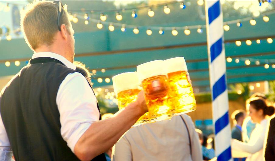 A person carrying four large pint glasses