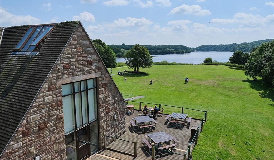 Image shows the cafe at Tittesworth Water on a sunny day, with the reservoir in the background, and green fields and trees in between