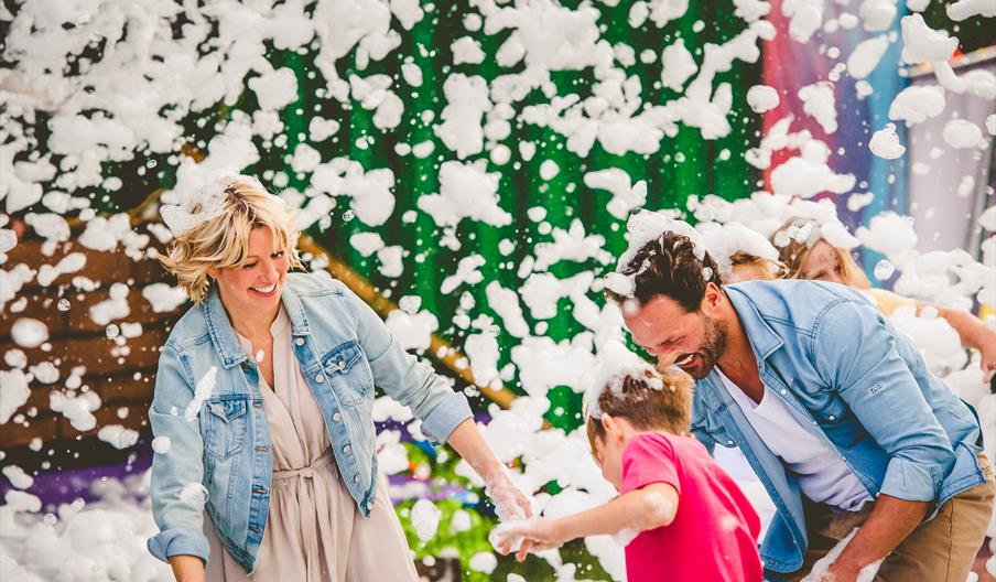 A family has fun at a foam party, as they are showered in bubbles