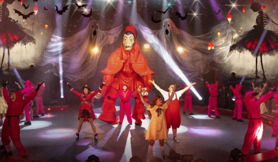 Performers in the Big Top at a circus, against a scary backdrop of skeletons and ghosts