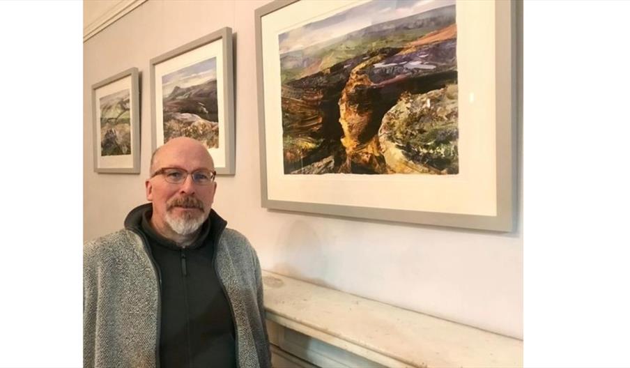 image of Giles Davies next to his paintings