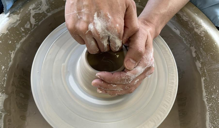 An overhead shot of someone throwing a pot on a potter's wheel