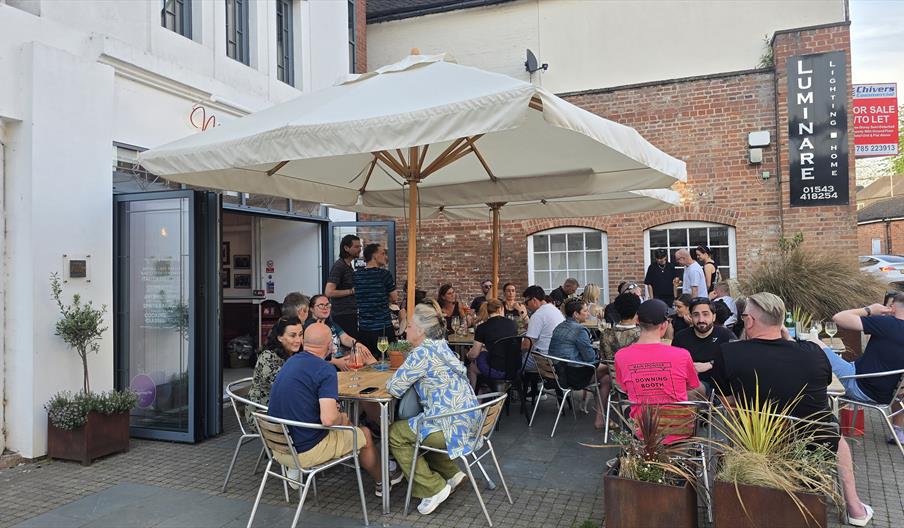 People sitting outside an Italian cafe under white umbrellas