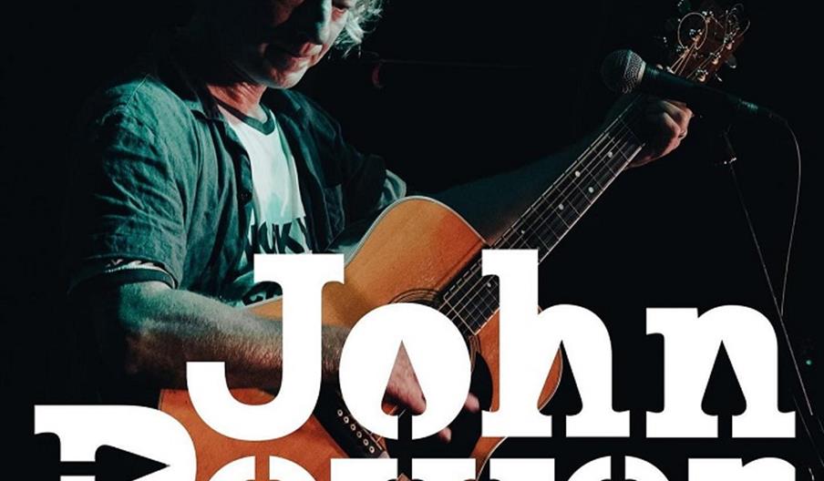 Image shows a man on stage with a guitar, and the words  'John Power' emblazoned on top