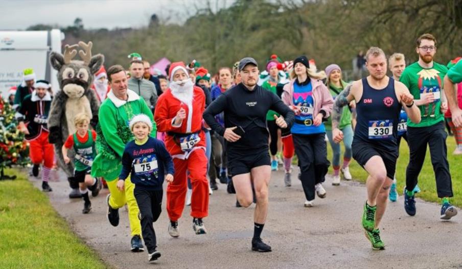 A large group of people in festive costumes running along a path in what looks like a park