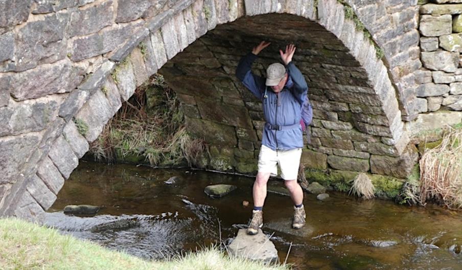 image of a man standing underneath a stone bridge