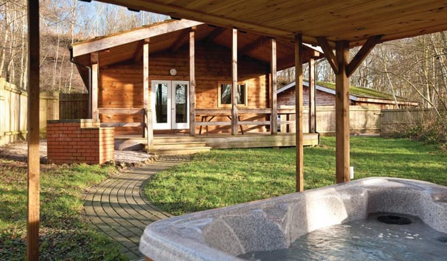 A hot tub on the porch of one lodge, looking over at another cabin, on a sunny day