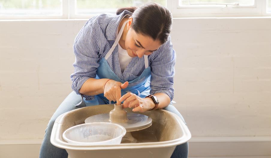 Woman working with clay at Potter's wheel