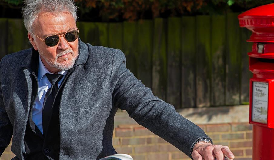 Paul Young stands by a red post box