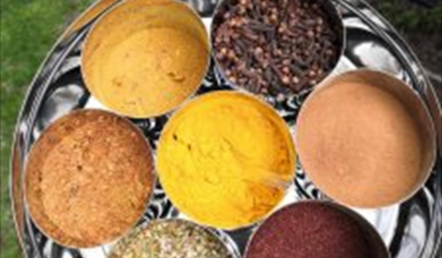 Photo shows a tray of different coloured spices in round containers