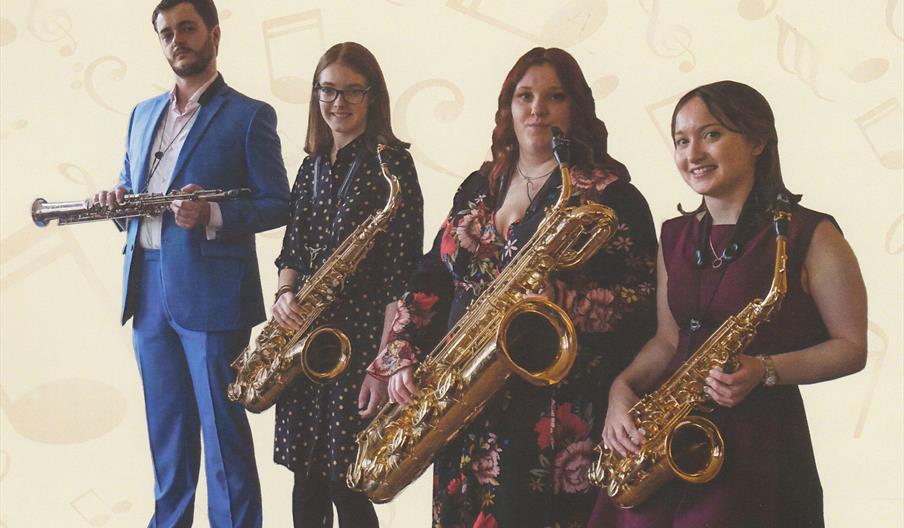 Four musicians stand in a line and pose for the camera