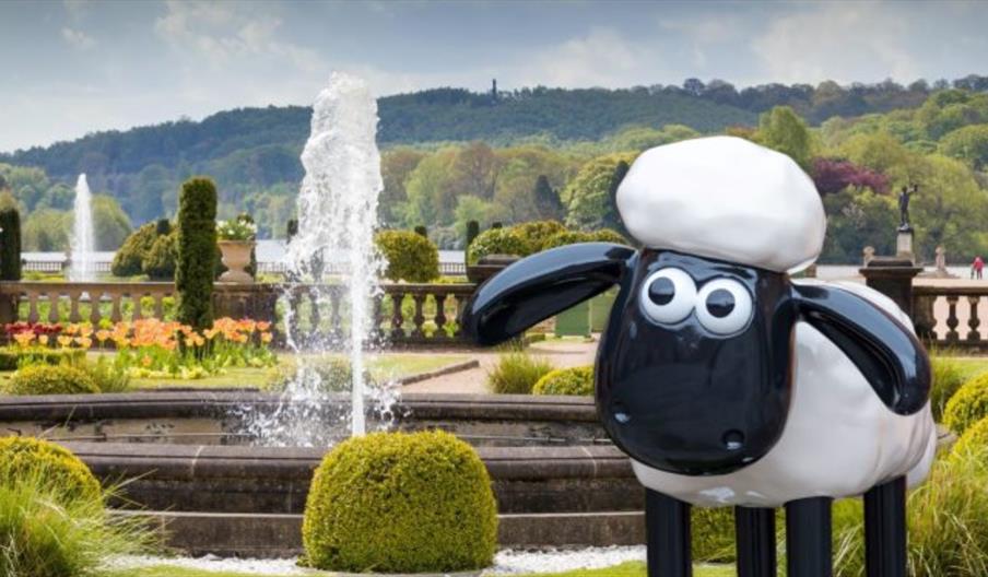 A model of Shaun the Sheep in the Italian Gardens at The Trentham Estate, with fountains, shrubbery, and the beautiful lake in the background