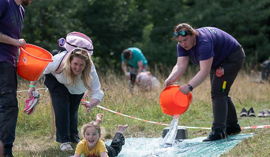 Child enjoying a water slide activity during a family outdoor event at The Wolseley Centre.