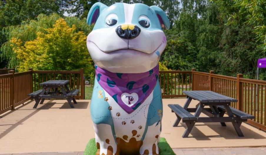 a staffy sculpture, who's name is muddy paws because of is painted dirty feet