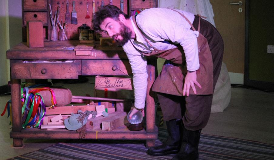 A toymaker in his workshop with lots of toymaking props
