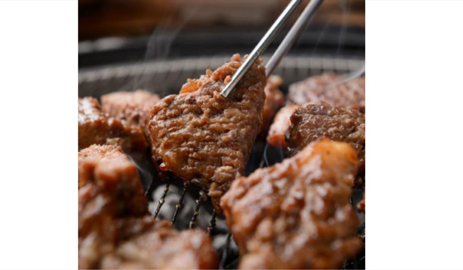 Grilled Korean pork cooking on a barbecue grill.