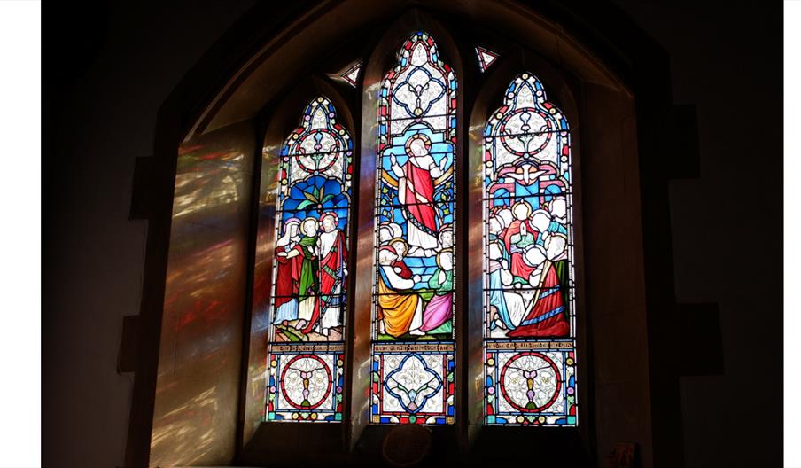 Colourful stained-glass church window illuminated by sunlight.