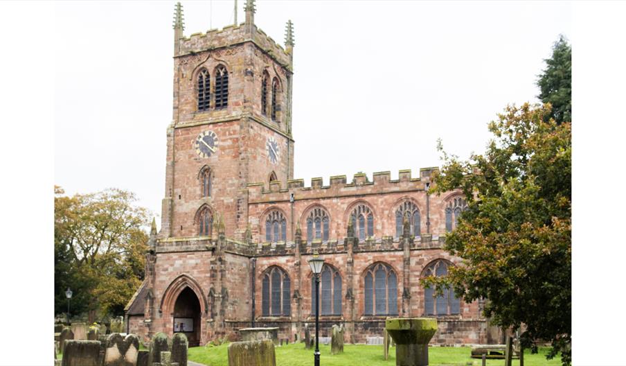 Holy Trinity historic stone church with a clock tower and surrounding churchyard.